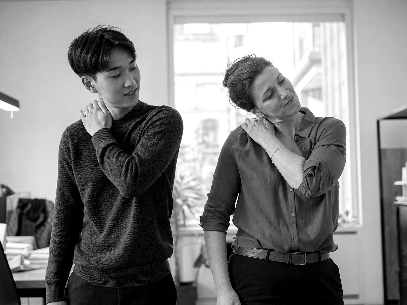 Deux salariés reproduisent un geste d’auto-massage de la nuque pendant un atelier en entreprise.